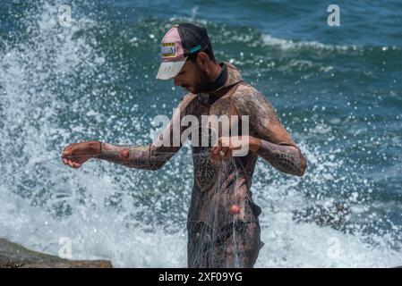 Alexandrie, Égypte. 26 juin 2024. Un jeune pêcheur égyptien vêtu d’une combinaison de plongée dispose son filet sur le front de mer Méditerranée d’Alexandrie, deuxième plus grande ville d’Égypte. (Crédit image : © John Wreford/SOPA images via ZUMA Press Wire) USAGE ÉDITORIAL SEULEMENT! Non destiné à UN USAGE commercial ! Banque D'Images