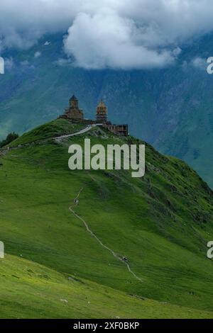 Stepantsminda, Géorgie - 30 juin 2024 : paysage avec l'église de la Trinité Gergeti sur le mont Kazbek à Stepantsminda, Géorgie. Banque D'Images