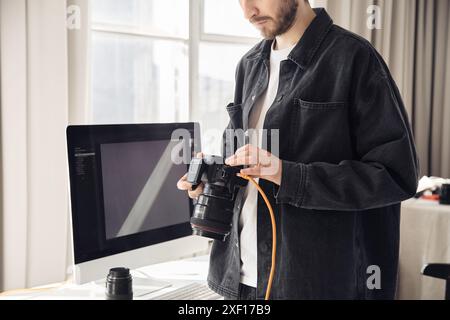 Photo recadrée d'un photographe barbu tenant un appareil photo professionnel et parcourant les images en studio, espace de copie Banque D'Images