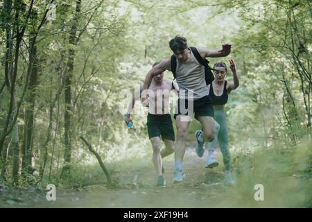 Groupe d'amis courant à travers le sentier forestier profitant de l'aventure en plein air Banque D'Images