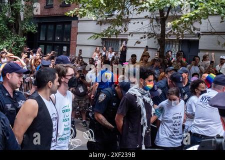 New York, États-Unis. 30 juin 2024. Le NYPD arrête les manifestants alors que la foule regarde pendant la manifestation. Des militants queer Pro-Palestine ont bloqué le défilé de la fierté de New York à Manhattan. Les manifestants étaient assis au milieu du parcours de défilé à Christopher Street et Waverly place. Plusieurs arrestations ont eu lieu, et le défilé a continué une fois qu'ils ont été enlevés. Crédit : SOPA images Limited/Alamy Live News Banque D'Images