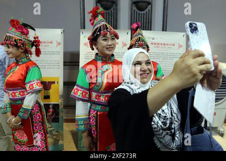 Amman. 30 juin 2024. Un visiteur prend un selfie avec des actrices vêtues de costumes ethniques au Centre culturel chinois à Amman, en Jordanie, le 30 juin 2024. Un événement de promotion de la culture chinoise du thé a eu lieu dimanche ici dans la capitale jordanienne avec des spectacles fascinants de musique et de danse et des costumes ethniques sur l'exposition mettant en valeur le caractère distinctif de la province du Yunnan, dans le sud de la Chine. Crédit : Mohammad Abu Ghosh/Xinhua/Alamy Live News Banque D'Images