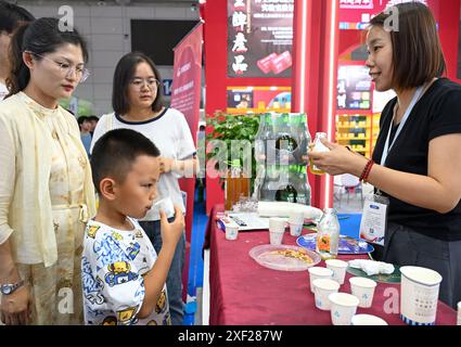 Urumqi, région autonome ouïgur du Xinjiang. 30 juin 2024. Un enfant goûte du jus d'argousier à la 8e exposition Chine-Eurasie à Urumqi, dans la région autonome ouïgur du Xinjiang, au nord-ouest de la Chine, le 30 juin 2024. Sur le thème 'nouvelles opportunités de la route de la soie, nouvelle vitalité pour la coopération eurasienne', l'exposition de cinq jours qui a ouvert ses portes le 26 juin a attiré plus de 1 900 participants de 50 pays, régions et organisations internationales, présentant plus de 6 000 variétés de produits. Crédit : Chen Shuo/Xinhua/Alamy Live News Banque D'Images