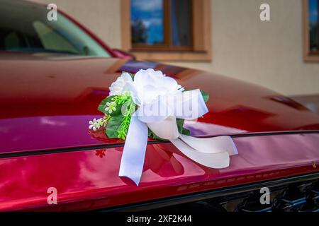 Décoration florale blanche sur capot de voiture rouge pour réception de mariage Banque D'Images