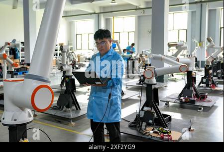 Jinan, province chinoise du Shandong. 12 mai 2024. Un technicien ajuste des robots dans un atelier de Zibo City, dans la province du Shandong de l'est de la Chine, le 12 mai 2024. Crédit : Yang Mingchao/Xinhua/Alamy Live News Banque D'Images