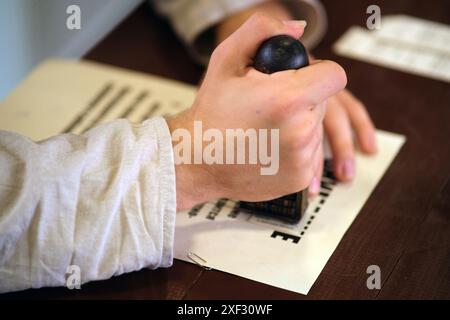 La main d'un homme met un sceau sur un morceau de papier, gros plan Banque D'Images