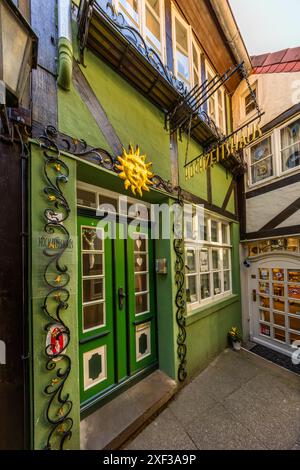 La Maison du Mariage (« wedding house ») sur Am Landherrnamt dans le quartier Schnoor de Brême est considérée comme l’un des plus petits hôtels du monde. Un ornement solaire doré et des ornements en fer forgé décorent l’entrée du bâtiment à colombages vert, dont la porte double verte présente des motifs de cœur gravés dans le verre. Am Landherrnamt, Brême, Allemagne. Banque D'Images