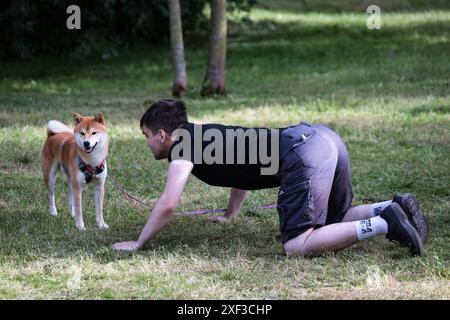 Un jeune homme se tient debout à quatre pattes devant un chien Shiba Inu pendant le festival Petshop Days au Primorsky Victory Park. Petshop Days est un festival annuel pour les animaux de compagnie et leurs propriétaires. Cette année, un véritable camp d’été a été préparé au Primorsky Victory Park avec des animations pour les propriétaires et leurs animaux de compagnie. SUP natation, agilité et plongée à quai, shopping au marché et abris d'aide, danse sur les traces de vos artistes préférés et conférences de conférenciers vedettes, ainsi que des concours et des cadeaux. (Photo Artem Priakhin/SOPA images/SIPA USA) Banque D'Images