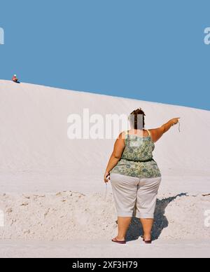 Femme obèse pointant près des dunes de sable Banque D'Images