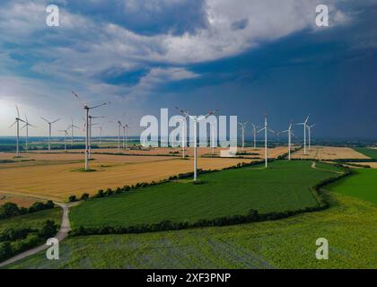 30 juin 2024, Brandebourg, Petersdorf : les nuages sombres d'un orage approchant passent au-dessus du paysage avec un parc éolien dans l'est du Brandebourg tôt le matin (vue aérienne avec un drone). Photo : Patrick Pleul/dpa Banque D'Images