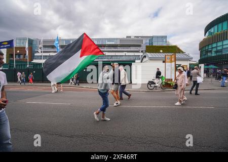 Wimbledon, Londres, Royaume-Uni 1er juillet 2024. Les manifestants pro-palestiniens se sont rassemblés devant le All England Lawn Tennis Club le premier jour des Championnats de Wimbledon avec une balle de tennis géante et des fraises « souillées de sang palestinien » pour manifester contre le parrainage par Barclay du Wimbledon qui finance, entreprises fournissant des armes et des technologies militaires utilisées par Israël à Gaza crédit : Amer Ghazzal/Alamy Live News Banque D'Images