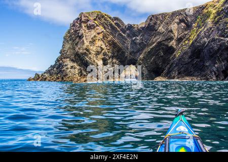 Kayak de mer vers une arche naturelle sur la côte du Pembrokeshire dans l'ouest du pays de Galles Banque D'Images