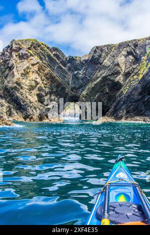 Kayak de mer vers une arche naturelle sur la côte du Pembrokeshire dans l'ouest du pays de Galles Banque D'Images