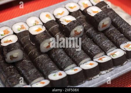 Une variété de rouleaux de sushi disposés soigneusement sur une table rouge vif, mettant en valeur un assortiment coloré et appétissant de cuisine japonaise Banque D'Images