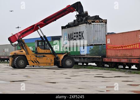 (240701) -- TIANJIN, 1er juillet 2024 (Xinhua) -- Un conteneur est chargé sur un train de marchandises Chine-Europe à destination de Moscou au port terrestre international de Tianjin, dans le nord de la Chine, Tianjin, le 1er juillet 2024. Un train de marchandises à destination de Moscou, en Russie, a décollé lundi du port terrestre international de Tianjin, marquant le lancement de la première ligne ferroviaire de marchandises Chine-Europe du port terrestre. Le train, chargé de 1 129 tonnes de marchandises, devrait arriver à Moscou dans environ 15 jours via le port d'Erenhot, dans la région autonome de Mongolie intérieure du nord de la Chine. (Xinhua/Li Ran) Banque D'Images