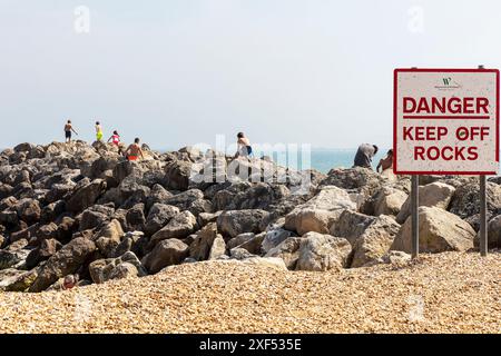 Danger, Keep off Rocks sign, Lyme Regis, Dorset, Royaume-Uni, Angleterre, enfants jouant sur des rochers dangereux, enfants sur des rochers, enfants ignorant le signe, ignorant le signe, Banque D'Images