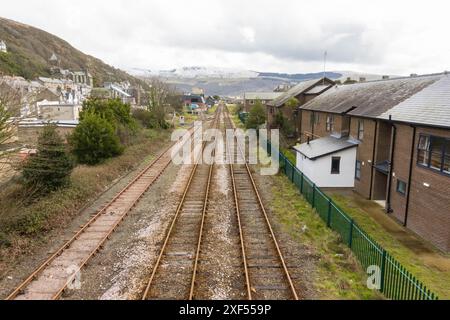 La Cambrian Coast Line traverse Barmouth, avec des montagnes enneigées en arrière-plan. Nord du pays de Galles Royaume-Uni. Mars 2024 Banque D'Images