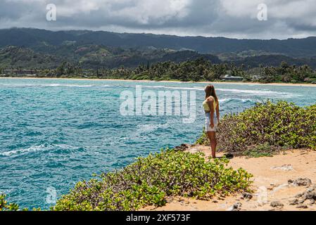 Une jeune femme est captivée par le paysage à couper le souffle d'une belle plage à Oahu, Hawaï. Elle regarde l'océan turquoise, encadré par Sway Banque D'Images