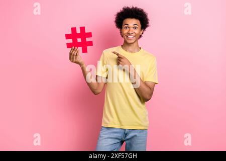 Portrait de la belle personne joyeuse indiquer la carte hashtag papier de maintien de bras de doigt isolé sur fond de couleur rose Banque D'Images