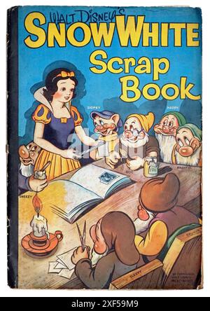 Album Blanche-neige de 1939, Walt Disney, avec permission. Montre Blanche-neige et les sept nains à une table, avec Blanche-neige collant des découpes dans un album à la lumière de la bougie. Banque D'Images