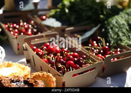 Savoureuses cerises rouges mûres dans des boîtes en carton sur la table à l'extérieur, gros plan Banque D'Images