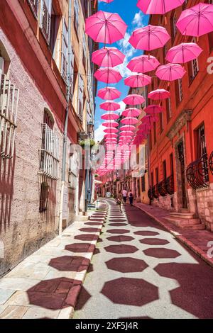 Parapluies roses flottants suspendus au-dessus de la rue Amiral de Grasse dans la vieille ville de Grasse sur la Côte d'Azur, Côte d'Azur, Provence, France Banque D'Images