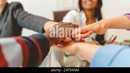 Un groupe de personnes se tiennent la main en cercle. Les gens sont de races et de sexes différents. La scène est celle de l'unité et de l'unité Banque D'Images