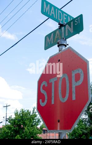 Panneaux de signalisation à une intersection au-dessus d'un panneau d'arrêt fané Banque D'Images