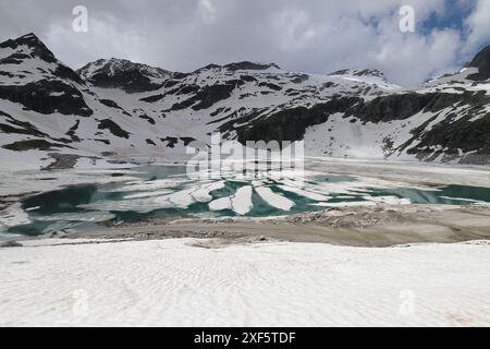 Vue grand angle du Weisssee vert émeraude encore partiellement gelé près du Großglockner, qui est encore couvert de floes de glace dérivantes Banque D'Images