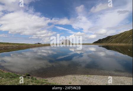 Plan grand angle de nuages blancs reflétés dans un lac de montagne, sommet de Rettenstein en arrière-plan Banque D'Images