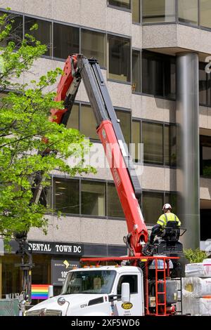 Washington DC, États-Unis - 3 mai 2024 : ouvrier de la construction utilisant une grue hydraulique pour livrer des matériaux de construction à un site de bureaux à Washington DC Banque D'Images