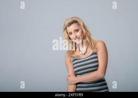 Belle mannequin dans une robe de mode rayée, met en valeur ses compétences de pose dans cette photo de studio, portant un collier cette image est adapté à une utilisation de la mode Banque D'Images