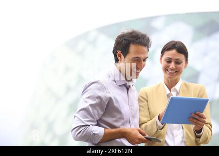 Homme d'affaires et femme d'affaires avec tablette et smartphone dans le centre d'affaires. Parc technologique de San Sebastian. Donostia. Gipuzkoa. Pays Basque. Spai Banque D'Images