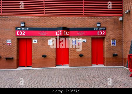 Manchester Trafford UK 29 juin 2024. Portes d'entrée du stade rouge vif étiquetées E32 sur un mur de briques, stand est, design urbain minimaliste. Banque D'Images
