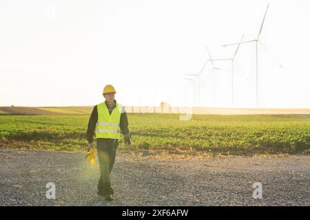 Ingénieur avec tablette numérique travaille sur un champ d'éoliennes. Banque D'Images