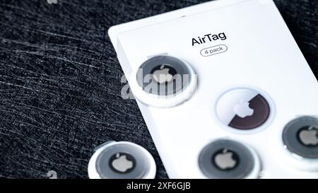 Jurmala, Lettonie - 25 06 2024 : gros plan de la boîte Airtag Apple blanche et 4 nouveaux aigtags sur fond noir. Banque D'Images