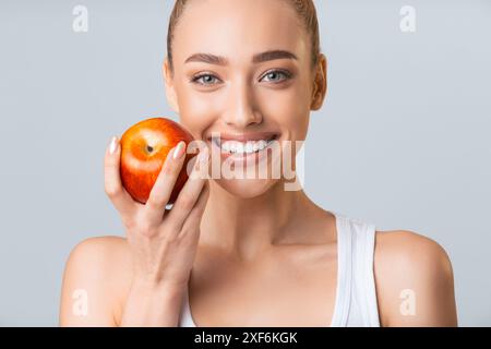 Jeune femme tenant Red Apple et souriant Banque D'Images