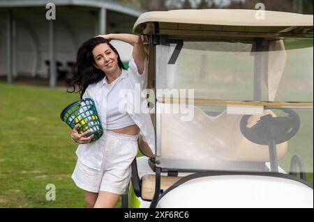 Femme active posant avec un équipement de golf près du véhicule à l'extérieur Banque D'Images