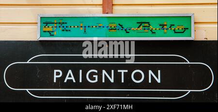 Panneau de gare de Paignton sur un mur en bois avec un indicateur de position de train au-dessus. Les lumières s'allument lorsqu'il se déplace le long de la piste. Banque D'Images