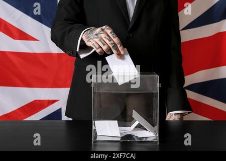 Voter jeune homme près des urnes contre le drapeau britannique, gros plan Banque D'Images