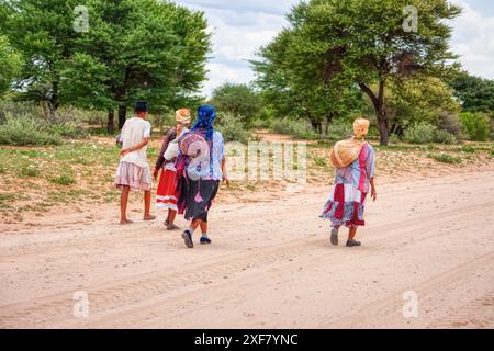 San People, quatre femmes africaines marchant sur un chemin de terre, village du Kalahari Banque D'Images