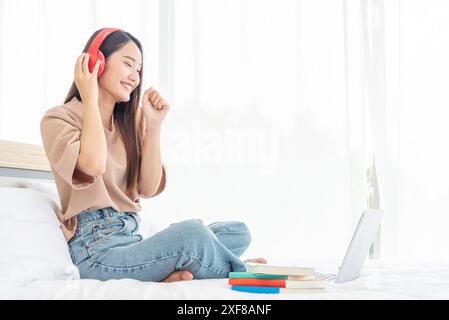 Détendez la femme tenant le livre lu sur le lit à l'aide d'écouteurs écouter de la musique. Jeune femme relaxation lisant l'esprit de loisirs à livre ouvert. Bonheur belle femme pe Banque D'Images