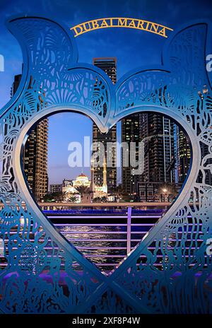 Dubaï, Émirats arabes Unis - 23 février. 2023 : les gratte-ciel de Dubaï et la mosquée Marina la nuit à travers un cadre de coeur dans la zone animée de la marina. Banque D'Images