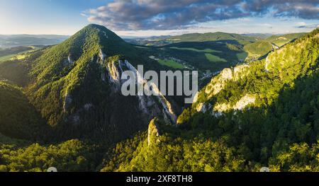 Vue aérienne de belles collines verdoyantes au coucher du soleil. Paysage coloré avec route rurale, arbres, herbe et bâtiments. Slovaquie Banque D'Images