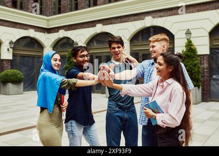 Caucasien, Arabes, Indiens et musulmans, étudiants multiraciaux debout à l'extérieur de l'université et interagissant, se préparant à un projet commun. Banque D'Images