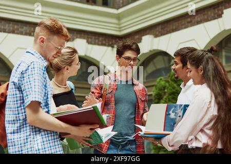 Des camarades de classe internationaux discutent de leurs prochains examens dans le jardin de l'université, parlent et se soutiennent mutuellement Banque D'Images