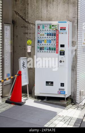 TOKYO, JAPON - 16 juin 2024 : un distributeur automatique de cigarettes dans la région de Meguro à Tokyo. Il y a un avis sur le mur indiquant quand un cendrier est disponible. Banque D'Images