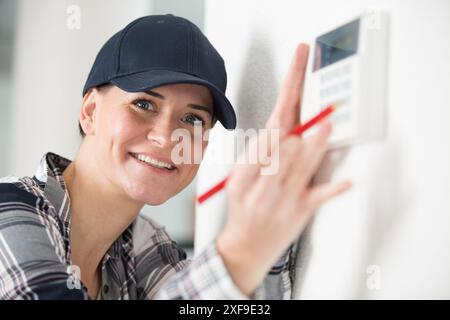 une femme ajustant le thermostat Banque D'Images