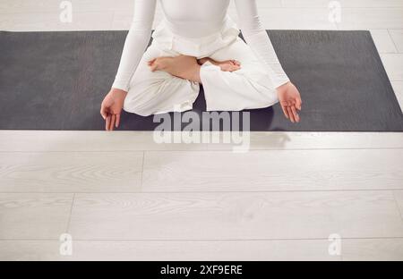 Siège de femme sportive Yogi sur tapis de près, s'entraîner sur tapis, faire de l'exercice de yoga, s'asseoir Banque D'Images