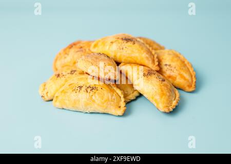 Tartes samosa fraîchement cuites avec de la viande saupoudrée de graines de pavot sur fond bleu, cuisine d'asie centrale, espace copie Banque D'Images